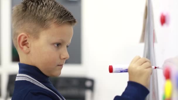 Мальчик пишет на доске в школе, решает упражнения — стоковое видео
