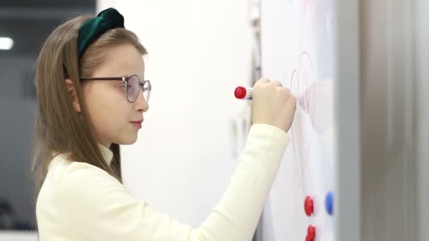 Gadis kecil menggambar penanda di papan tulis di sekolah. Anak yang pintar. — Stok Video