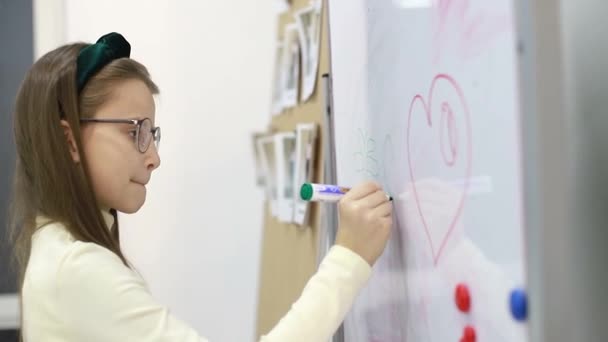 Holčička si ve škole kreslí na tabuli značku. Chytré dítě. — Stock video