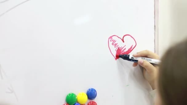 Kleine Mädchen neben der Tafel in der Grundschule. Kinder spielen mit bunten Magneten auf weißem Brett — Stockvideo