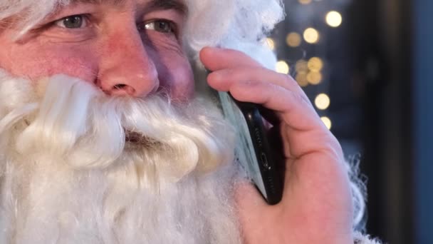 Портрет Санта Клауса, який розмовляє на смартфоні. Санта спілкується з дітьми по телефону. — стокове відео
