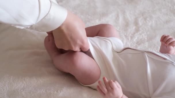 Mama wechselt Windeln für Baby, verschwommener Hintergrund. Das Neugeborene bewegt seine Beine. Babypflege — Stockvideo