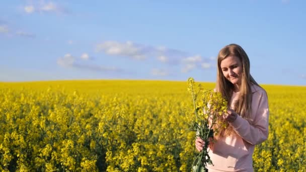 Szczęśliwa młoda blondynka na żółtym polu rzepakowym. rzepak, rośliny polne, rośliny uprawne — Wideo stockowe