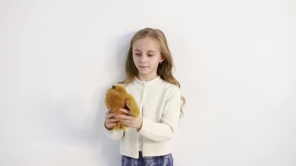 Дитина з ведмедем у руках, маленька дівчинка тримає плюшевого ведмедя в руках . — стокове відео