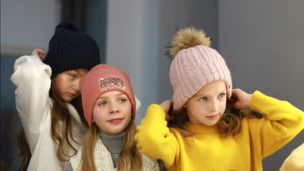 Los niños miden sombreros frente al espejo, los niños compran en la tienda — Vídeos de Stock