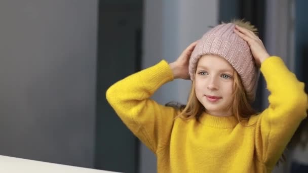 Küçük bir kız aynanın önünde bir şapka ölçer, çocuklar şık giyinir.. — Stok video