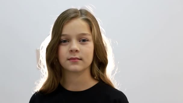Egy tinédzser lány portréja, egy kislány a kamerába néz. — Stock videók