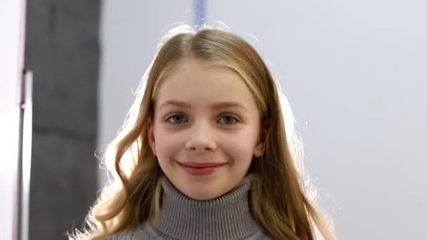 Gezicht van kleine meisje close-up, gelukkig klein meisje op grijze achtergrond — Stockvideo