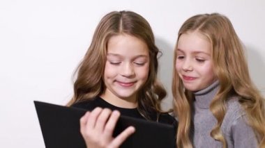 İki güzel kız kardeş tablet ekranına bakın, akıllı çocuklar akıllı teknolojiyi kullanıyorlar..