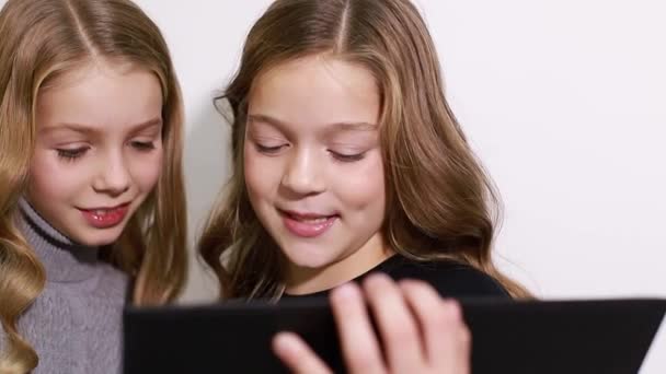 Två vackra små systrar tittar på surfplattan, smarta barn med smart teknik. — Stockvideo