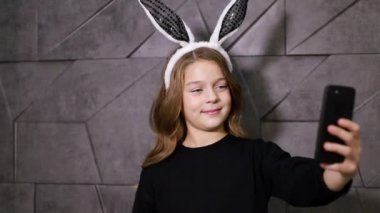 Genç kız eğleniyor, tavşan kulaklarıyla fotoğraf çekiyor.