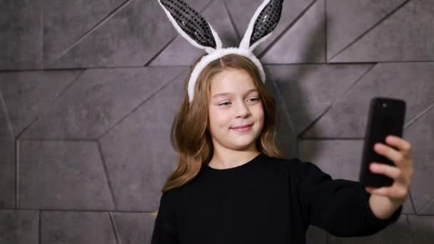 Νεαρή έφηβη κοπέλα που διασκεδάζει, φωτογραφίζεται με αυτιά κουνελιού — Αρχείο Βίντεο