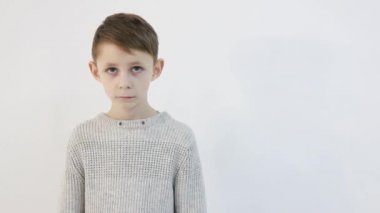 Beyaz arka planda komik küçük çocuk, üzgün çocuk kameraya bakıyor.