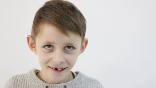 Petit garçon drôle sur un fond blanc, enfant triste regarde la caméra — Video