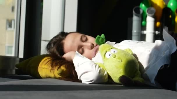 Söt liten flicka sover i sin lilla säng, hon kramade en mjuk leksak — Stockvideo