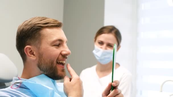 一次去看牙医 病人看着镜子 发现有一颗病了的牙 嘴巴和牙齿都很健康 现代牙科学 — 图库视频影像