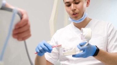 Diş hekimine git, dişlerin önlenmesi ve tedavi edilmesi. Diş hekimi doğru diş fırçalama tekniğini gösterir. Diş ve ağız sağlığı konsepti.
