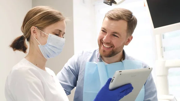 Dental treatment in a modern dental clinic. The young man is satisfied with the treatment, the patient communicates with the doctor. The concept of dental health and a beautiful smile