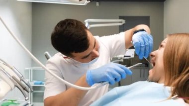 Modern diş hekimliğinde hastaların dişlerini muayene eden bir diş hekimi. Tek kullanımlık tıbbi maskeli doktor..