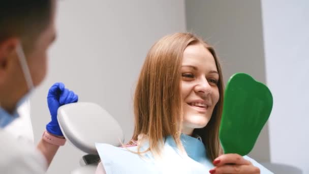 Młoda Kobieta Szczęśliwy Klient Patrząc Lustro Uśmiech Zębiczny Gabinecie Stomatologicznym — Wideo stockowe