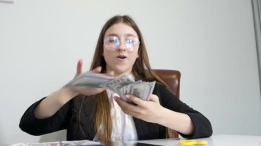 Genç kız kameraya doğru para saçıyor. Çocuklar için işletme okulu