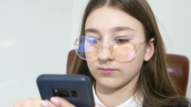 十代の女の子でFormalwear話す上の携帯電話に座っているオフィスで白の背景 ビデオ4K — ストック動画