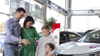 Mutlu aile yeni araba alıyor, araba satıcısı babasıyla tokalaşıyor yeni araba için aileyi tebrik ediyor, 4K video.