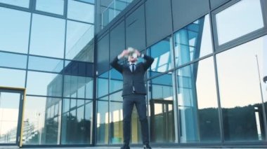 Erkek işadamı çok para saçıyor. Ofis merkezinin yakınında tatmin olmuş genç bir iş adamı. Para yağmuru, düşen dolarlar. 200 karede çekim