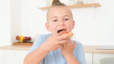 Genç bir aile lezzetli bir şekilde İtalyan pizzası yiyor, masada mutfakta oturuyor, iletişim kuruyor ve eğleniyorlar. Fast food yemeği.