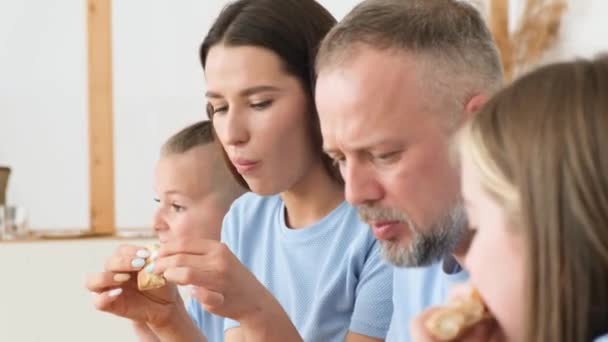 若い家族はおいしいイタリアのピザを食べて テーブルのキッチンに座って 彼らは通信し 楽しみを持っています ファーストフードランチ — ストック動画