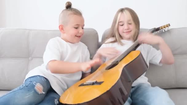 Αδέρφια Διασκεδάζουν Καθισμένοι Στον Καναπέ Παίζουν Κιθάρα Ευτυχισμένα Παιδιά Που — Αρχείο Βίντεο