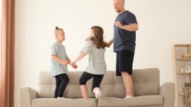 Babam çocuklarla oynuyor, kanepede zıplıyorlar. Mutlu bir aile evde dinleniyor. Yavaş çekim