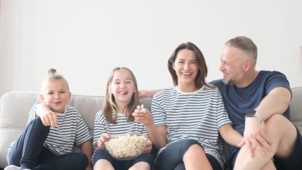 家里快乐的一家人在沙发上吃爆米花看电视 一群人在网上看了一部搞笑的电视剧 一边吃着爆米花 一边笑 一边在家里玩乐 — 图库视频影像