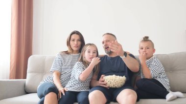 Aile, anne baba ve çocuklar patlamış mısır yiyip televizyon izliyor. Bir grup insan televizyon izler, patlamış mısır yer ve evde dinlenir.