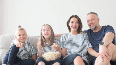 Evdeki mutlu aile kanepede patlamış mısır yiyor ve televizyon seyrediyor. Bir grup insan internette komik bir TV dizisi izliyor ve evde eğlenirken patlamış mısır yiyip gülüyorlar.