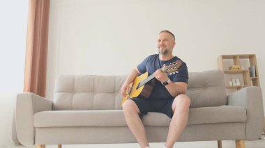 Babam kanepede otururken gitar çalar, ailesi onun yanında oturur. Mutlu bir aile evde dinleniyor.