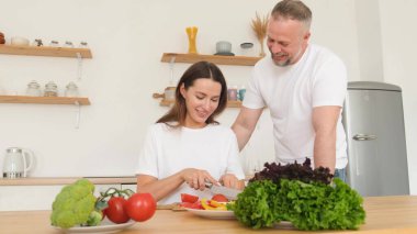 Kadın ailesi için salata hazırlıyor. Mutlu aile evdeki mutfakta. Vejetaryen yemeği. 4k video