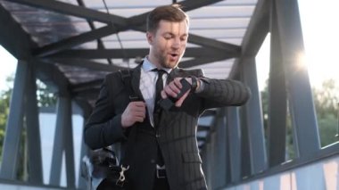 Evrak çantalı genç adam aceleyle işe gidiyor. Bir ofis çalışanı akıllı bir saate bakar ve bir iş toplantısına gider. Ofis resmi takım elbiseli bir işçi şehirde dolaşır..