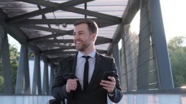 İş elbiseli genç bir adam köprüden geçer ve gülümser. İş adamı şehrin sokaklarında gün batımının arka planında yürüyor. Yavaş çekim