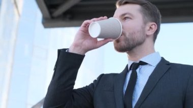 İş elbisesi içinde yakışıklı bir adam Amerika 'daki iş merkezinin yakınında lezzetli bir kahve içiyor. Kahve molası. Enerji içeceği.