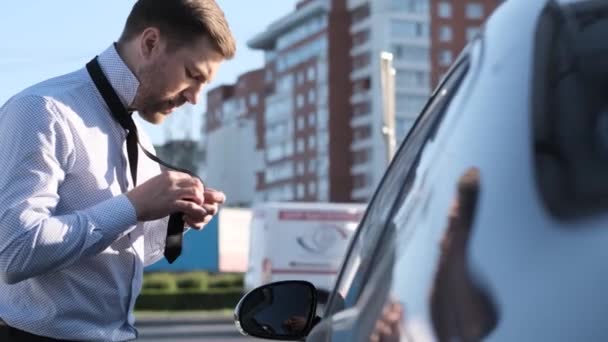 若いビジネスマンは彼の車の窓の外を見て 通りにネクタイをつけます ビジネスミーティングのために時間外の男は遅れている 事業概念 — ストック動画