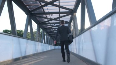 Elinde evrak çantasıyla şık giyinmiş bir yönetici işe koşuyor. Bir çalışan, şehir merkezinde açık havada koşarken ofis resmi bir takım elbiseyle bir iş çantasını tutar..