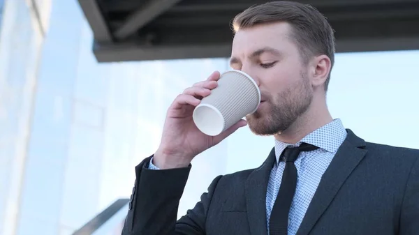Handsome man in business suit drinking delicious coffee near business center in USA. Coffee break. Energy drink.
