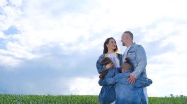 Aile, mavi gökyüzünün arka planında. Ebeveynler ve çocuklar aile yürüyüşü yapar. Mutlu bir aile. Çocuklar yeşil bir alanda rüya görür. Yavaş çekim