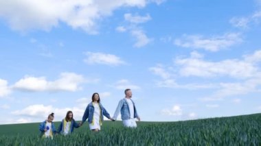 Oğlu ve kızı buğday tarlasında yürüyen mutlu bir çiftçi ailesi. Aile el ele tutuşuyor ve doğa ile eğleniyor. Yavaş çekim