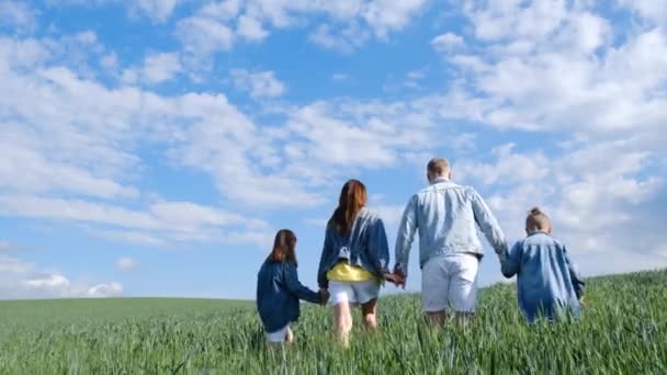 青空を背景に畑で家族 両親と子供の家族のハイキング 幸せな家族だ 子供たちは緑の分野で夢を見る スローモーション — ストック動画