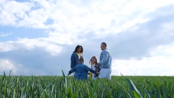 幸せな家族は緑のフィールドを歩く 彼らはデニムの服を着ている 家族の概念 — ストック動画