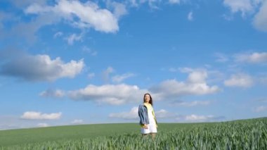 Güzel, yalnız bir kız kollarını açmış yeşil bir tarlanın ortasında duruyor. Kendini özgür hissediyor ve doğanın tadını çıkarıyor. 4k video