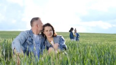Yaz günü aile yürüyüşü, arkadaş canlısı aile kavramı. Çocuklar ve mutlu ebeveynler yeşil bir tarlanın ortasında yürürler. Mutlu bir aile.