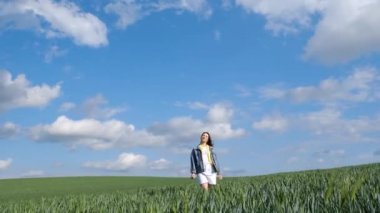 Çekici kadın yeşil bir alanın ortasında kollarını ağır çekimde açıyor. Yalnız bir kadın kendini özgür hisseder. Esmer kadın doğanın tadını çıkarıyor.